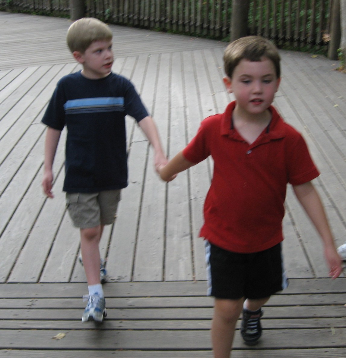 two young boys holding hands on a playground.