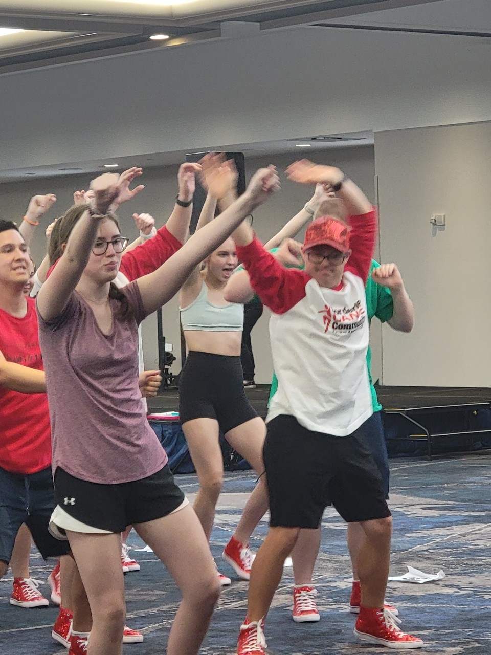 dancers in athletic gear doing coordinated dance moves during rehearsal.